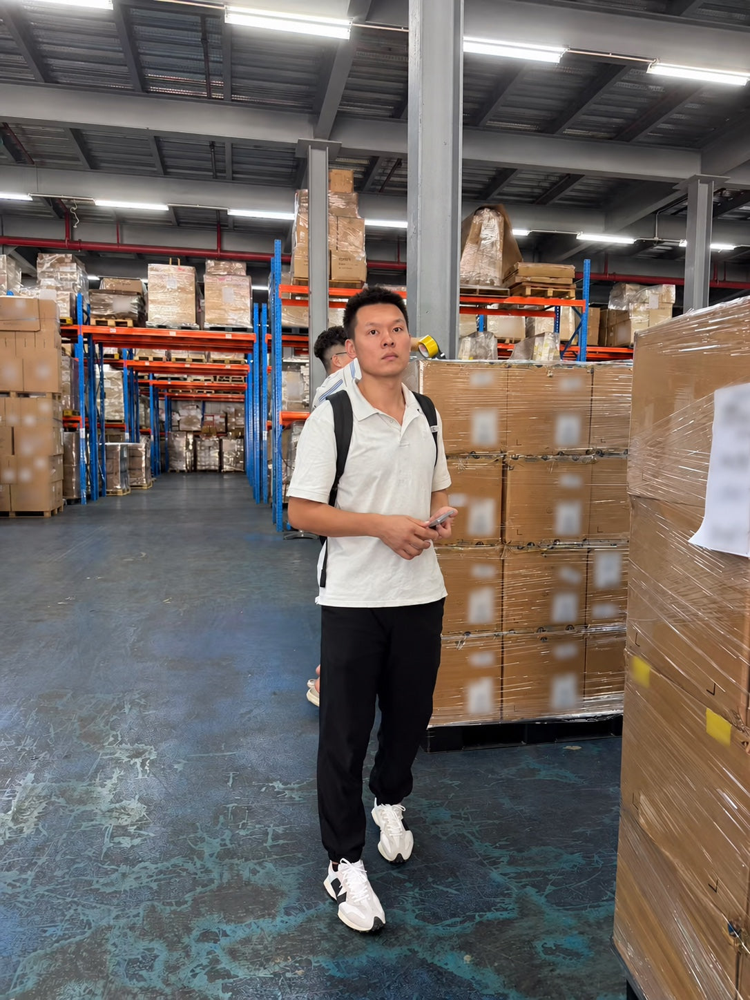 Joseph working on site among stacked cartons in a China warehouse