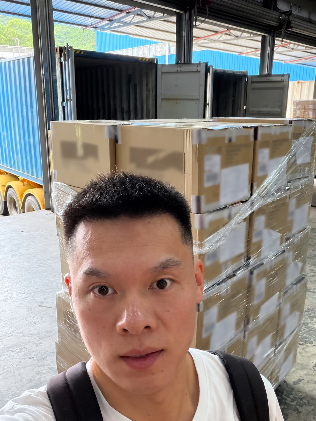 Joseph documenting sourcing work beside warehouse cartons